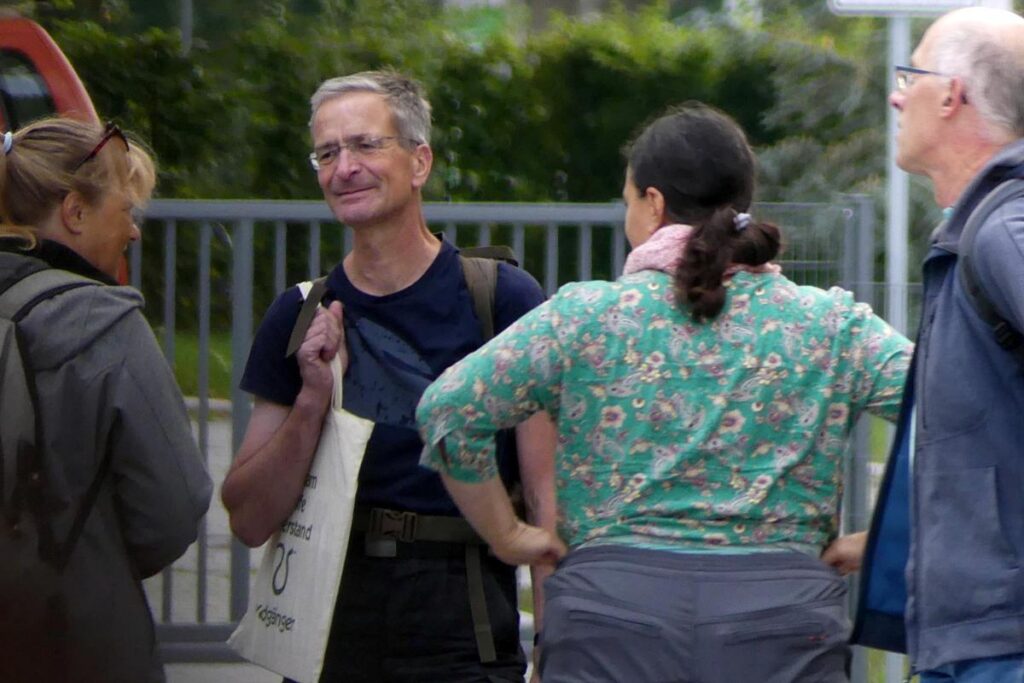 Gruppe von vier Personen im Gespräch bei der Anreise zum "Marsch für das Leben" von denen eine Person einen weißen Beutel des Antaois-Verlags trägt.