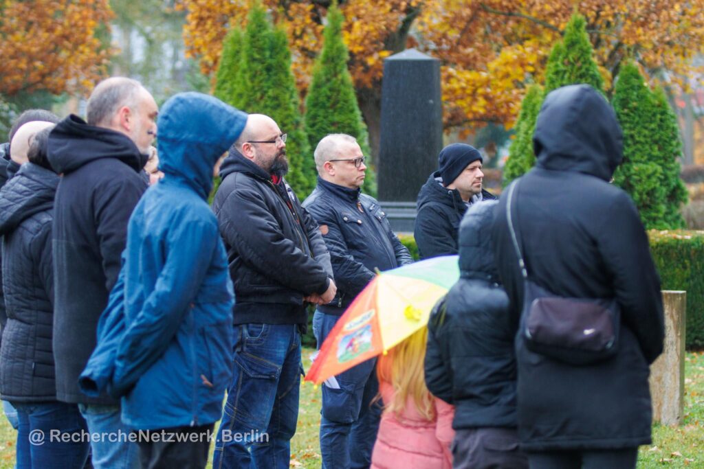 Foto von mehreren Personen, darunter Patrick Wieschke und Steven Arndt, die auf einem Friedhof stehen und in eine Richtung schauen