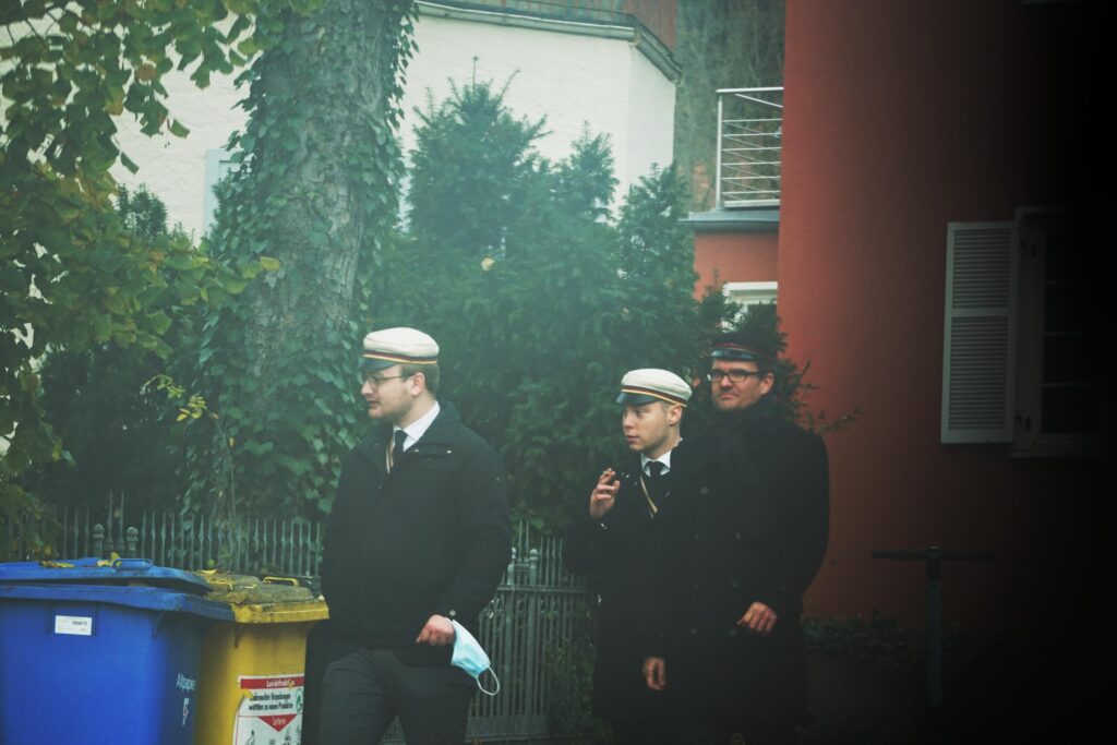 Foto von Florian Ockenfels, Henning Eggers und Henning Kläfker am 14.11.2021 beim Volkstrauertag in Jena. Ockenfels und Eggers tragen Germania Mützen, Kläfker eine Mütze des Burgkellers.