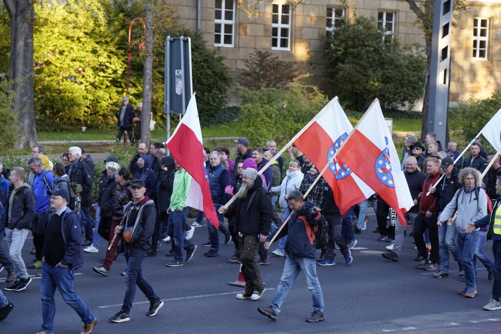 Foto eines AfD-Aufmarsches in Erfurt am 21.09.2022. Am rechten Bildrand ist Volker Hanemann zu sehen. Um ihn herum laufen andere Erwachsene in dunkler Kleidung, einige von ihnen tragen große rot-weiße Fahnen mit sich.