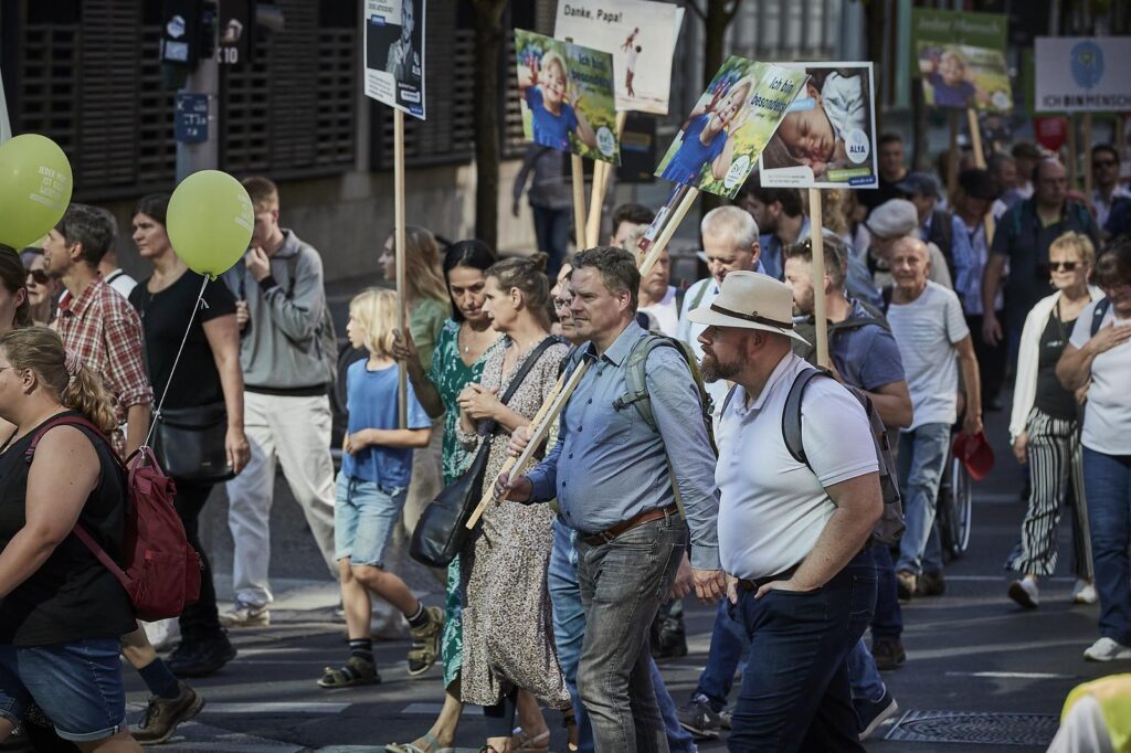 Foto von Jens Scherbel am "Marsch für das Leben" 2023. Scherbel trägt ein Schild auf dem ein Foto von einem Kind und der Text "Ich bin besonders!" und das Logo "BVL" zu sehen ist. Andere Personen tragen weitere Schilder. Teilweise mit dem gleichen Motiv wie Scherbel.