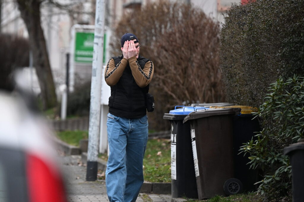 Bild von Luis Rupprecht auf dem Weg zu einer IB Veranstaltung in Chemnitz. Rupprecht trägt ein Basecap und versucht sein Gesicht mit den Händen zu verdecken.