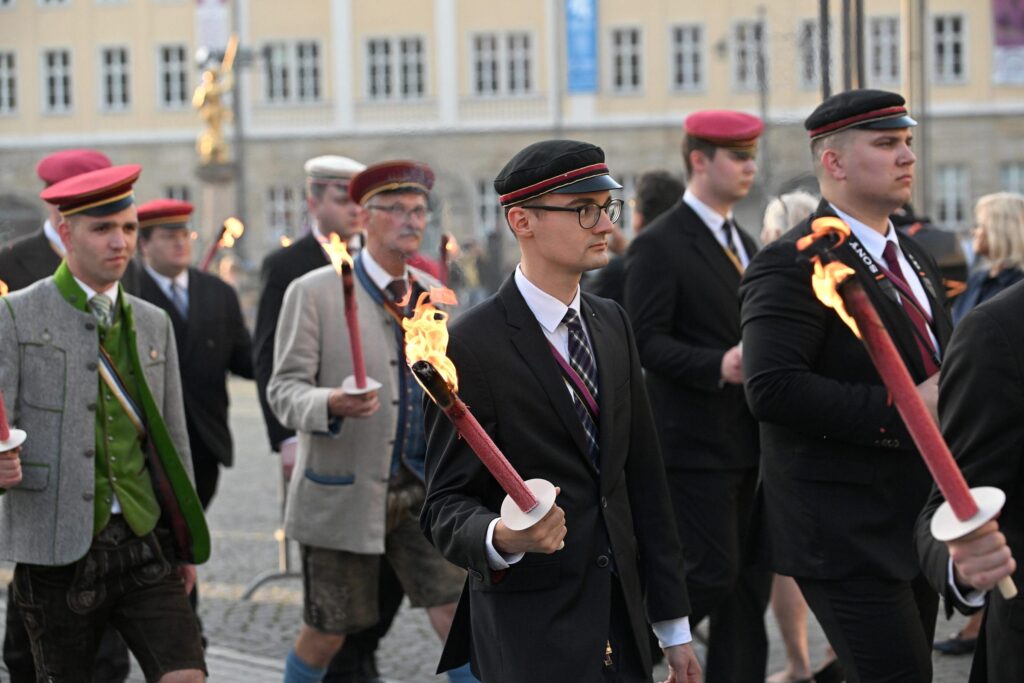 Foto von Friedrich Hunger und Ron Schade beim DB-Burschentag in Eisenach am 13.06.2025. Hunger ist im Vordergrund zu sehen mit einer brennenden Fackel in der rechten Hand und in Burgkeller-Couleur. Im Hintergrund laufen weitere Burschenschafter in Couleur und mit Fackeln.