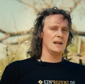 Porträtbild von Jörg Tonndorf auf dem dieser ein T-Shirt mit dem Schriftzug "EINPROZENT.DE" trägt.