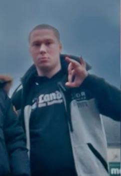 Ein Foto von Julian aus dem Januar 2025 aus Berlin. Er trägt einen Pullover von „Landser“, eine graue Thor Steinar-Jacke und macht mit seiner linken Hand das „White Power“ - Zeichen.