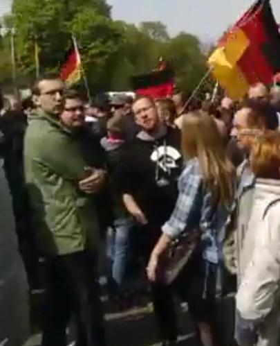 Foto von Oskar Wasielewski, Christian Heilmann und Lars Seyfarth am 1.5.2017 bei der AfD in Erfurt. Wasielewski trägt eine Brille und eine grüne Jacke. Er und seine Begleiter sind von vielen anderen Teilnehmenden umringt, im Hintergrund sind Deutschlandflaggen zu sehen.