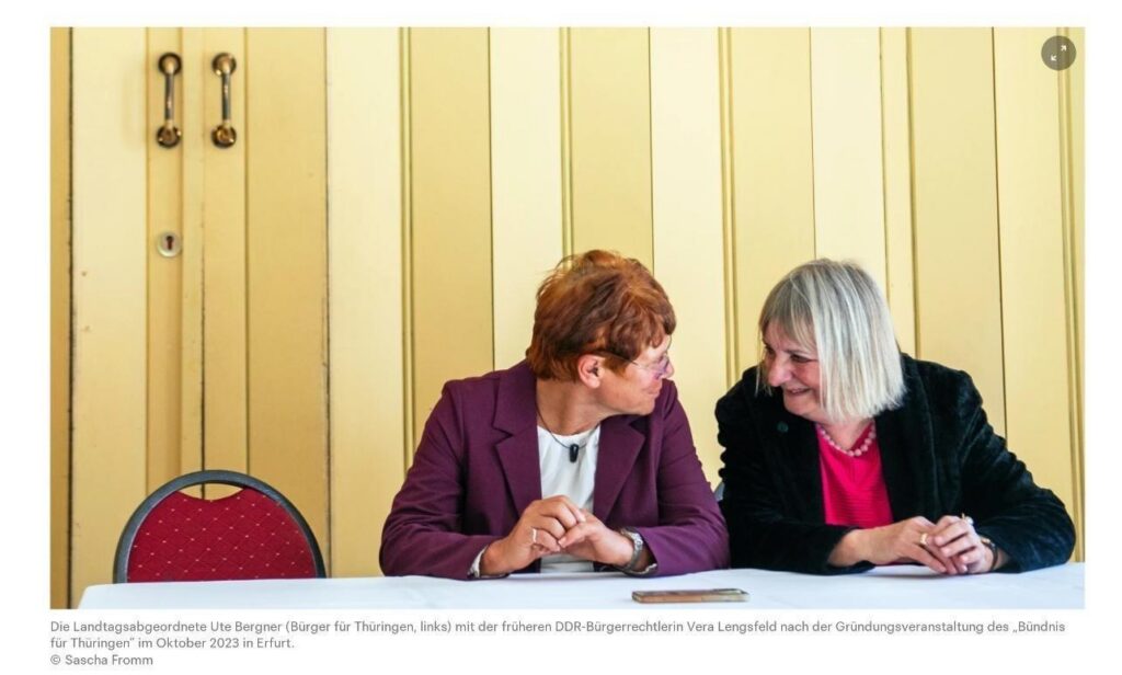 Ute Bergner und Vera Lengsfeld sitzen eng nebeneinander an einem weißen Tisch und blicken sich an, Lengsfeld lacht. Die originale Bildunterschrift lautet: "Die Landtagsabgeordnete Ute Bergner (Bürger für Thüringen, links) mit der früheren DDR-Bürgerrechtlerin Vera Lengsfeld nach der Gründungsveranstaltung des 'Bündnis für Thüringen' im Oktober 2023 in Erfurt."